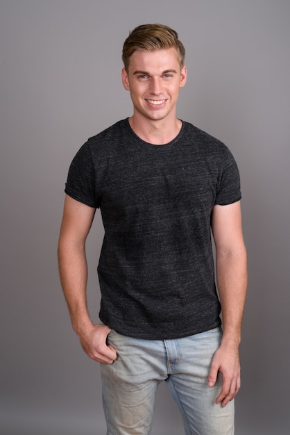 Photo young handsome man with blond hair wearing gray shirt on grey wall