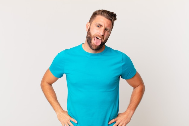 Young handsome man with cheerful and rebellious attitude, joking and sticking tongue out. fitness concept