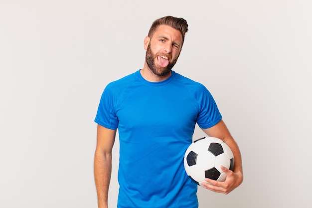 Young handsome man with cheerful and rebellious attitude, joking and sticking tongue out. soccer concept