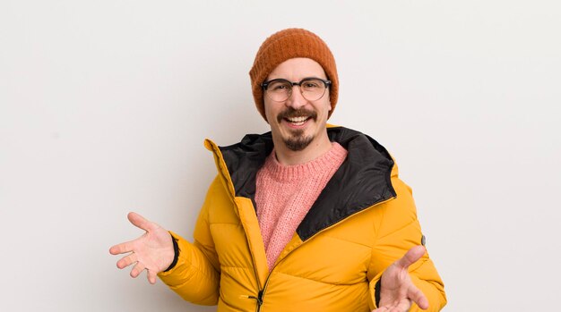 Young handsome man with a coat against white wall