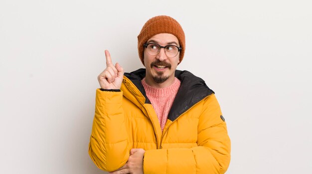 Young handsome man with a coat against white wall