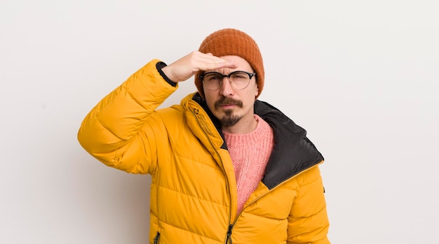 Young handsome man with a coat against white wall