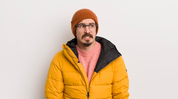 Young handsome man with a coat against white wall