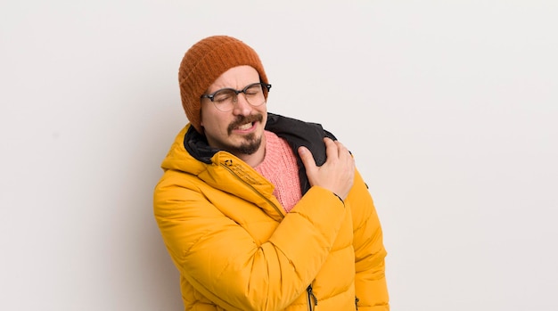 Young handsome man with a coat against white wall