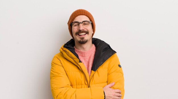 Young handsome man with a coat against white wall