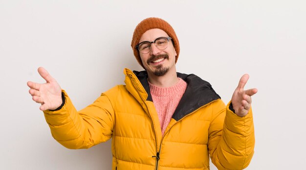 Giovane uomo bello con un cappotto contro il muro bianco