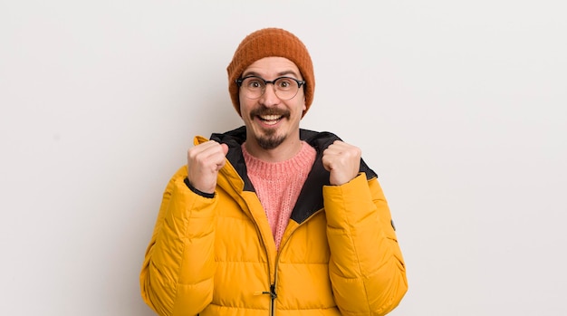 Young handsome man with a coat against white wall