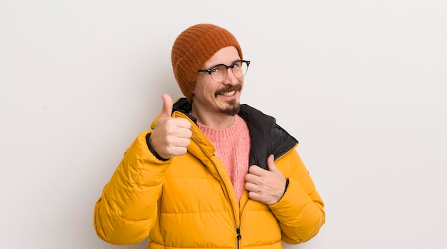 Young handsome man with a coat against white wall