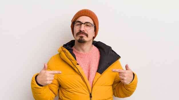 Young handsome man with a coat against white wall