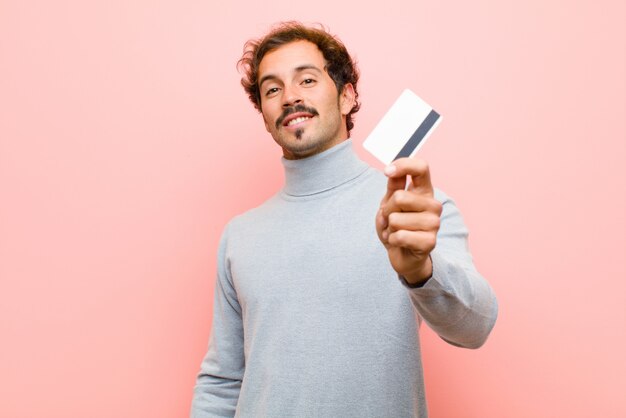 Young handsome man with a credit card against pink flat 