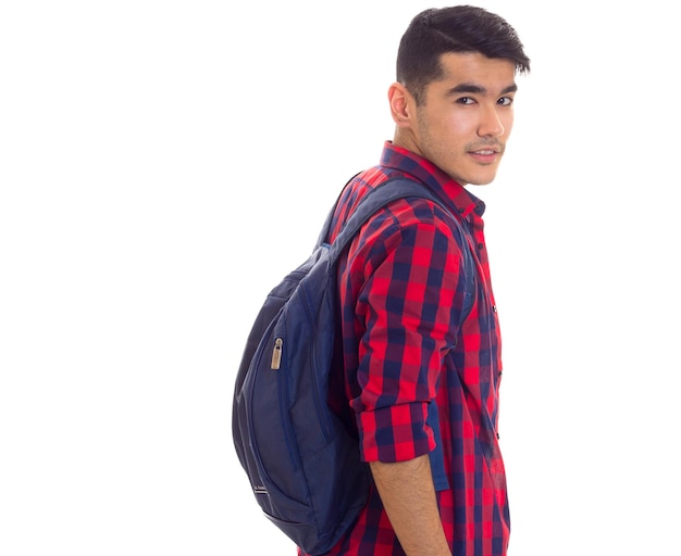 Young handsome man with dark hair in white Tshirt and checkered shirt with blue backpack in studio