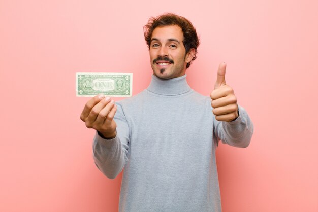 Photo young handsome man with dollar banknotes against pink flat wall