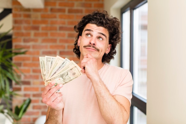 Photo young handsome man with dollar banknotes at home interior