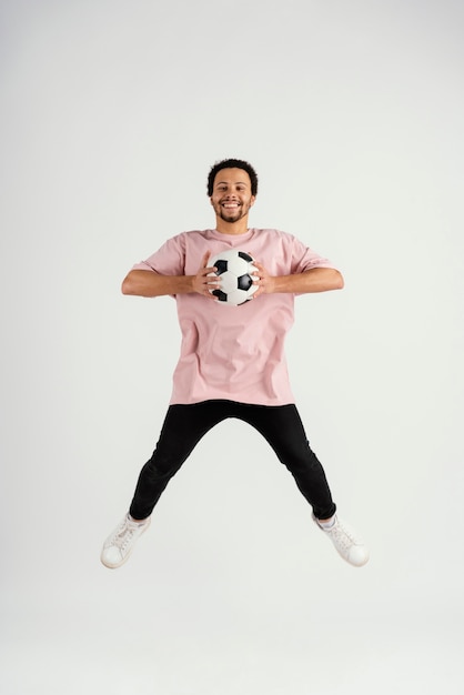 Photo young handsome man with football ball jumping