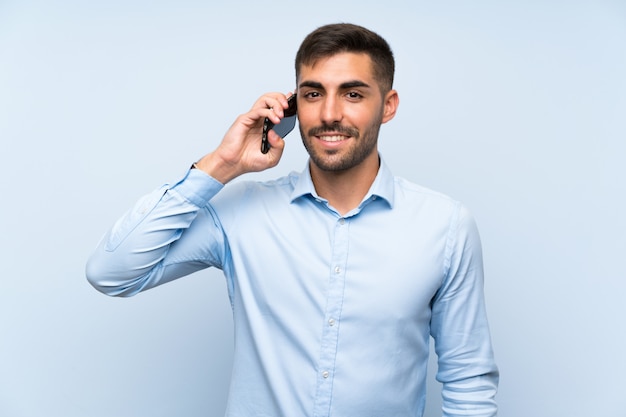 Young handsome man with his mobile blue wall