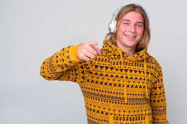 young handsome man with long blond hair against white wall