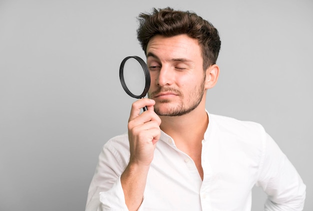 Young handsome man with a magnifying glass search or find\
concept