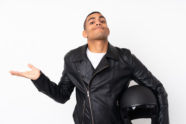 Young handsome man with a motorcycle helmet over isolated white wall having doubts with confuse face expression