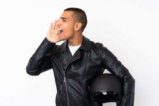 Young handsome man with a motorcycle helmet over isolated white wall shouting with mouth wide open