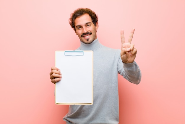 Young handsome man with a sheet of paper against pink flat 