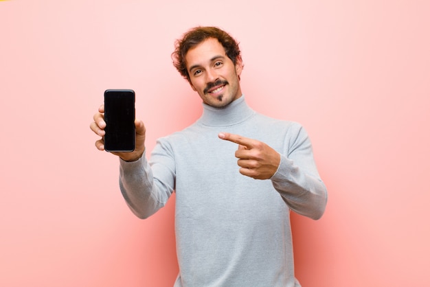 Young handsome man with a smart phone against pink flat 