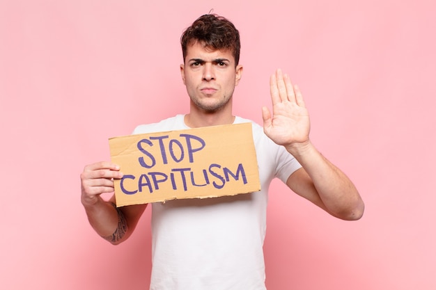 Young handsome man with stop capitalism banner