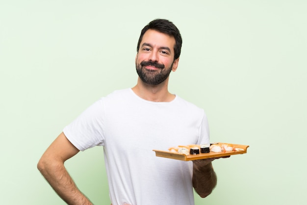 Young handsome man with sushi posing with arms at hip and smiling