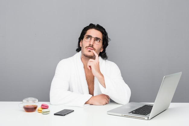 Young handsome man working after a shower looking sideways with doubtful and skeptical expression.