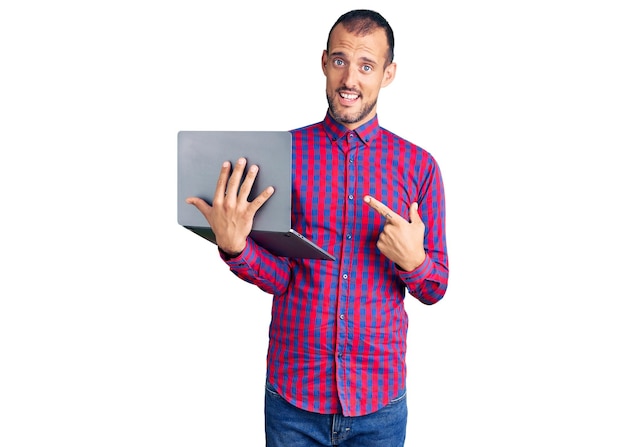 Young handsome man working using computer laptop smiling happy pointing with hand and finger