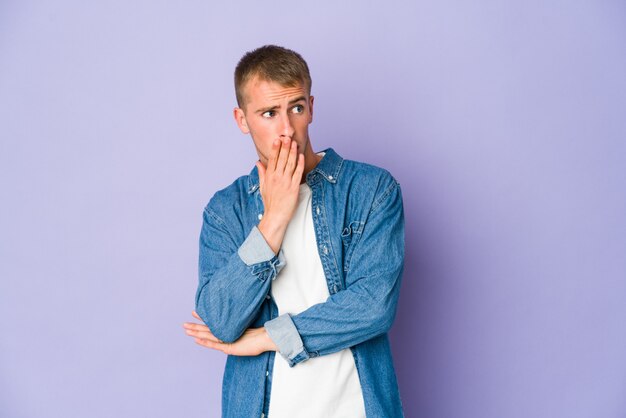 Young handsome man yawning showing a tired gesture covering mouth with hand