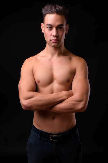  young handsome multi ethnic man shirtless against black wall