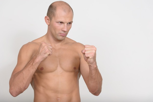 young handsome muscular bald man shirtless against white space