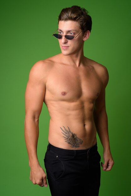  young handsome muscular man shirtless against green wall