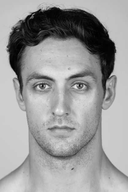 Young handsome muscular man with wavy hair shirtless isolated in black and white