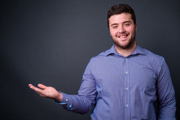 young handsome overweight bearded businessman on gray