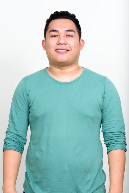 young handsome overweight Filipino man against white wall