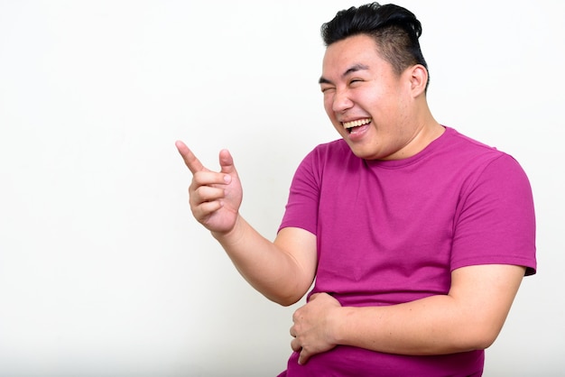 young handsome overweight Filipino man against white wall