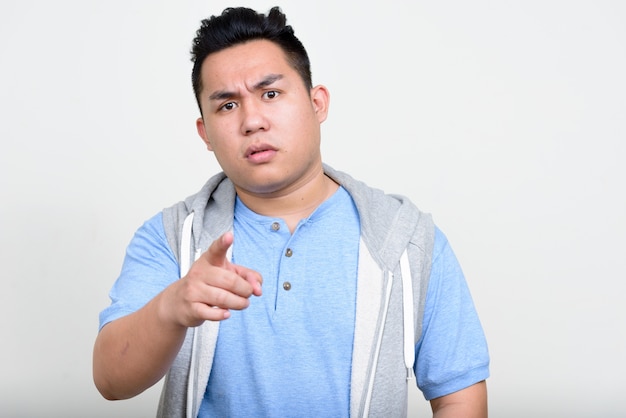  young handsome overweight Filipino man against white wall