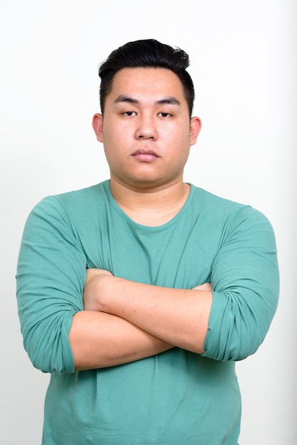  young handsome overweight Filipino man against white wall