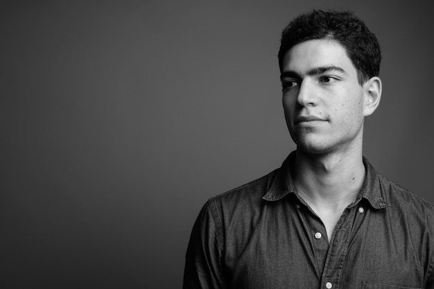 young handsome Persian businessman against gray wall in black and white