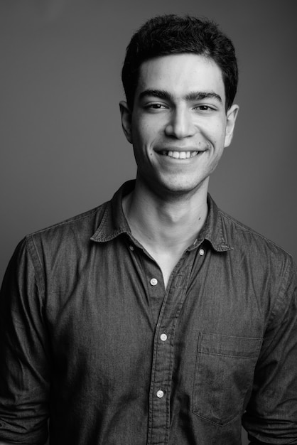 young handsome Persian businessman against gray wall in black and white