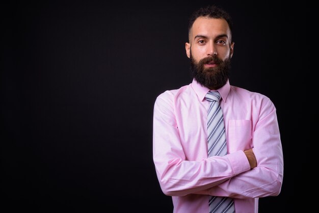  young handsome Persian businessman with dreadlocks against black wall