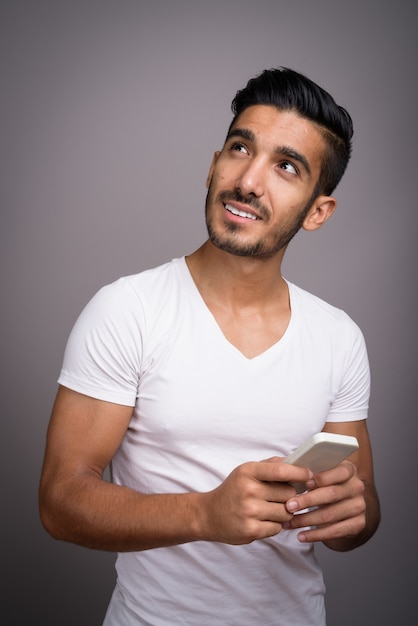 Young handsome Persian man against gray background