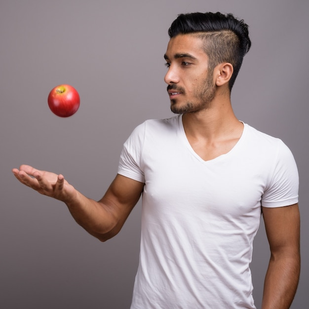 Young handsome Persian man against gray background