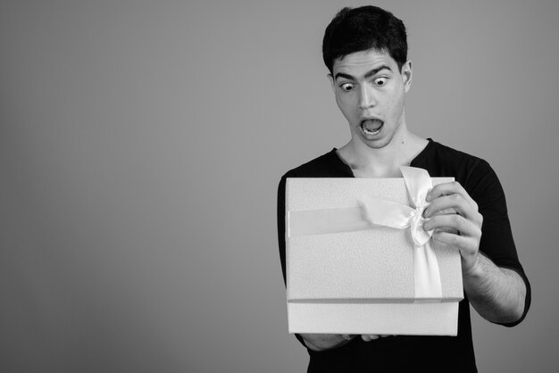  young handsome Persian man against gray wall in black and white