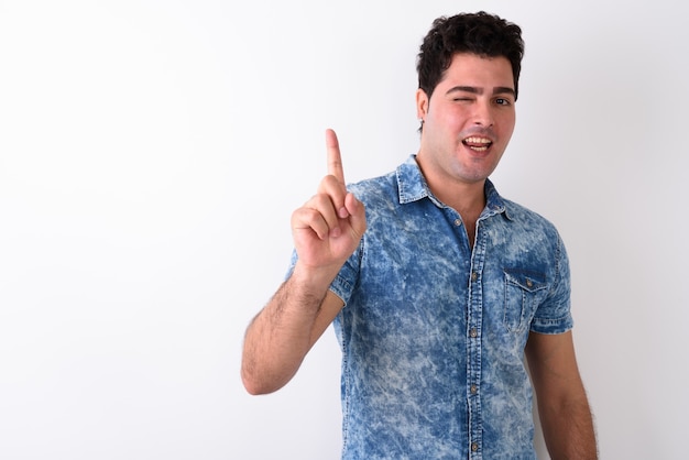 Young handsome Persian man against white wall