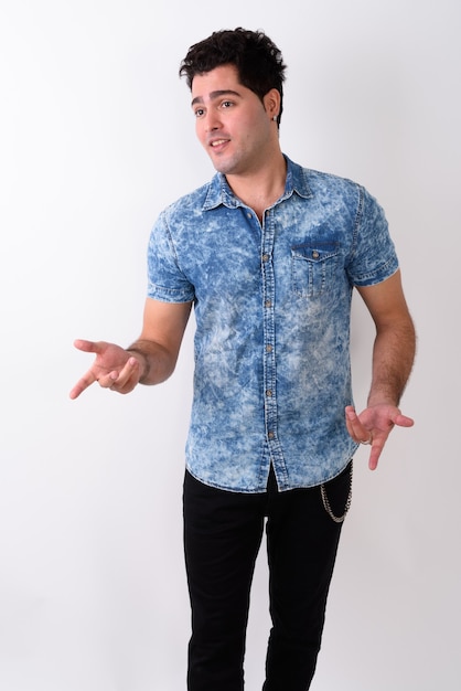 Young handsome Persian man against white wall