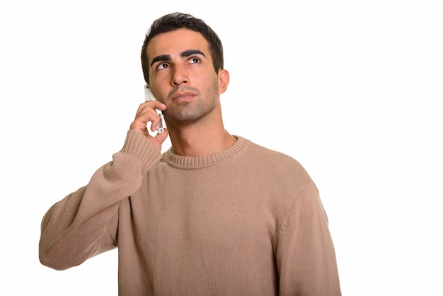 Young handsome Persian man talking on phone while thinking