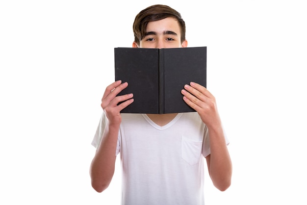 young handsome Persian teenage boy hiding behind a book