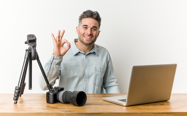 Young handsome photography teacher cheerful and confident showing ok gesture.